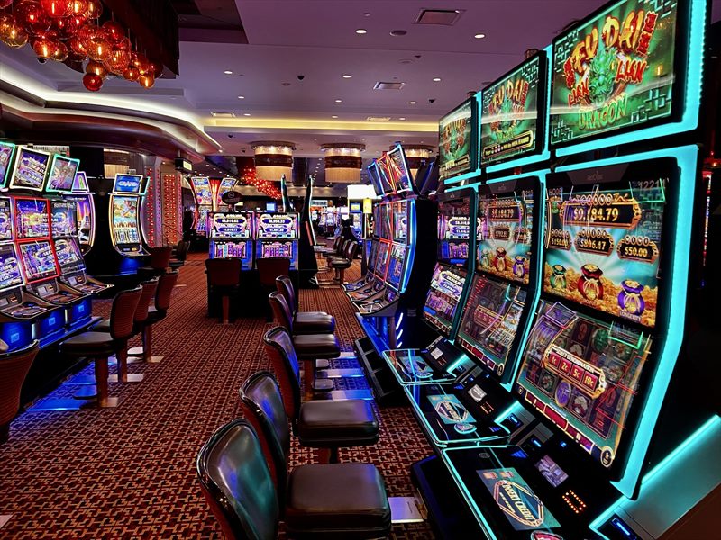Pasillo de máquinas tragamonedas iluminadas en un casino físico